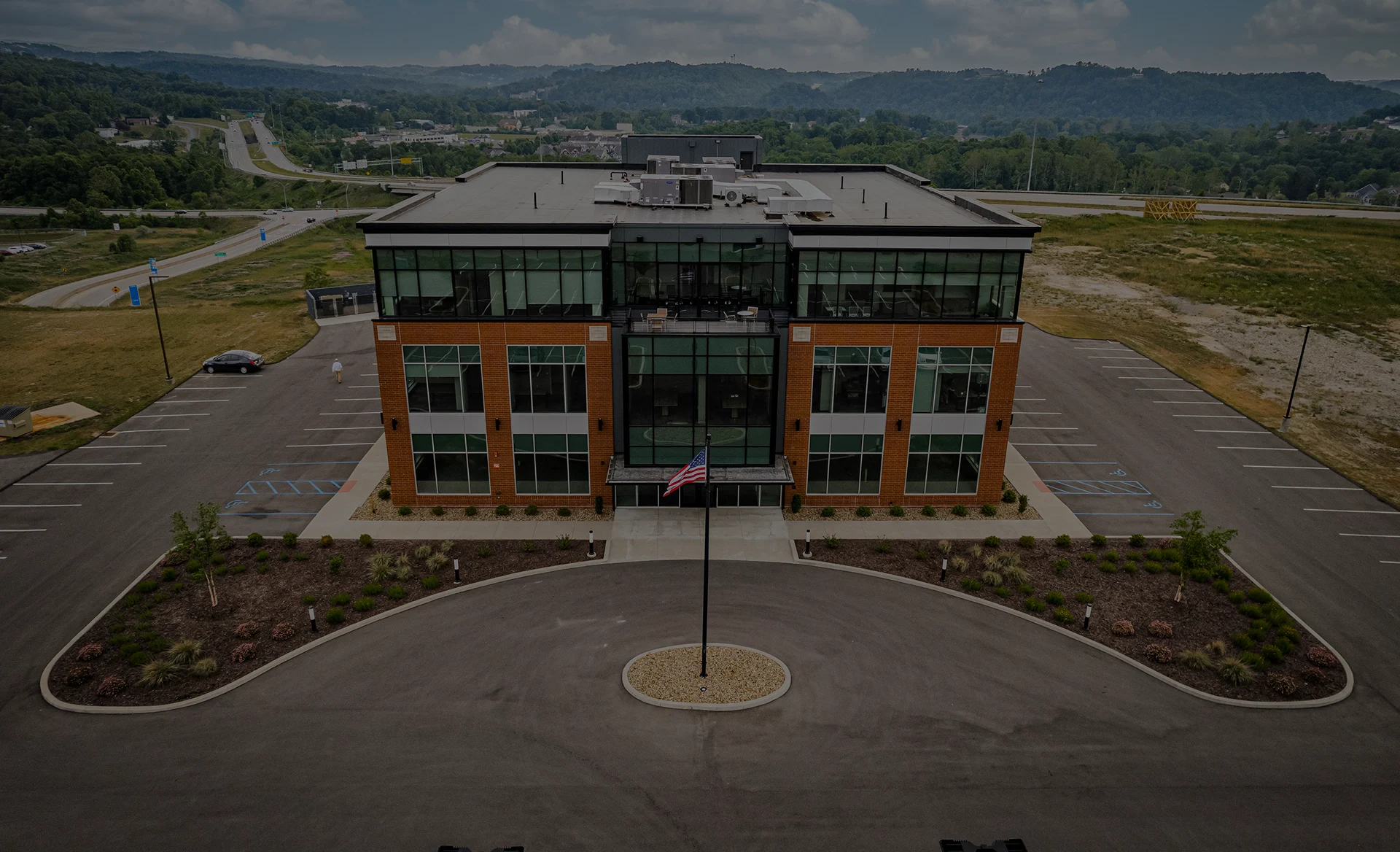 Aerial view of a large building featuring a flag atop its roof, showcasing its architectural design and surrounding area