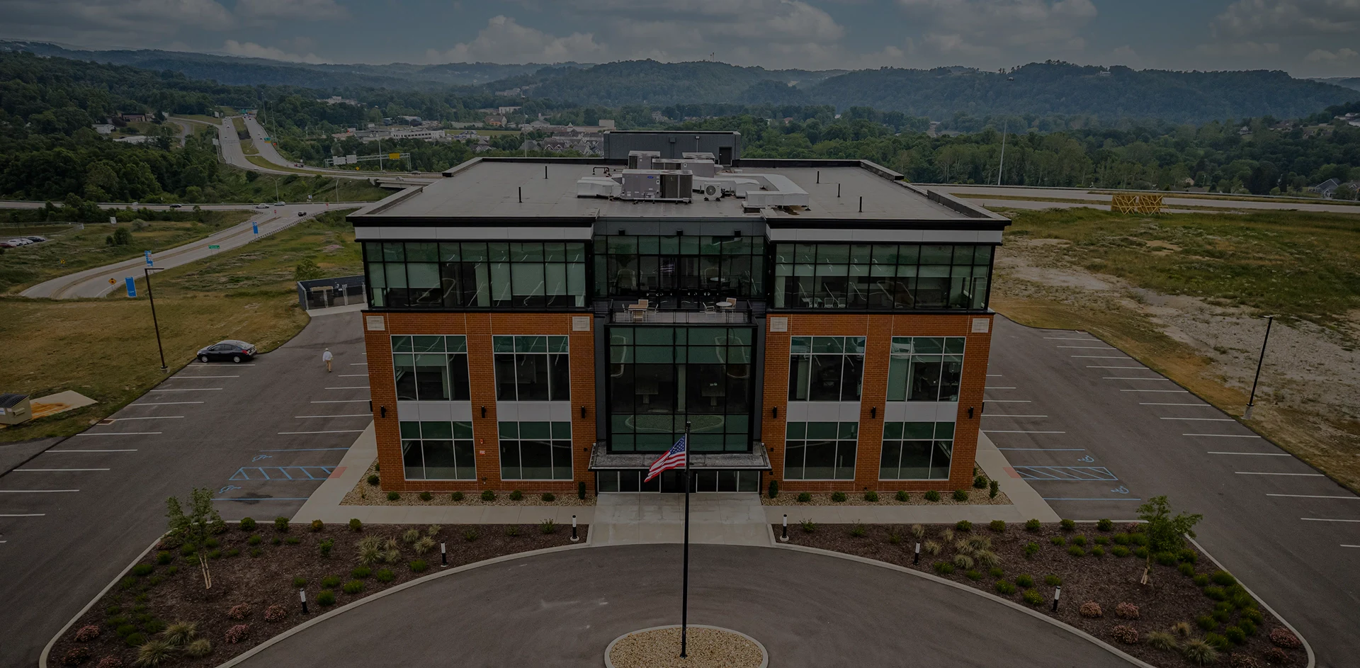 Aerial view of a large building featuring a flag atop its roof, showcasing its architectural design and surrounding area